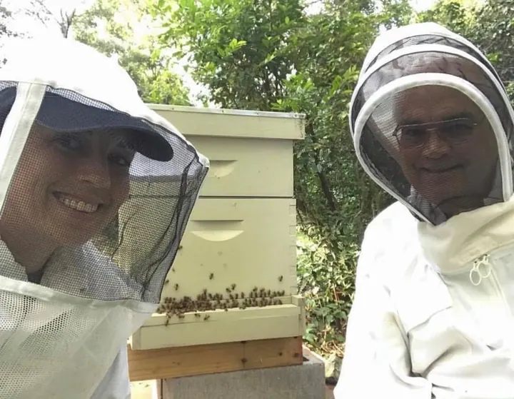 Two beekeepers smiling beside a hive